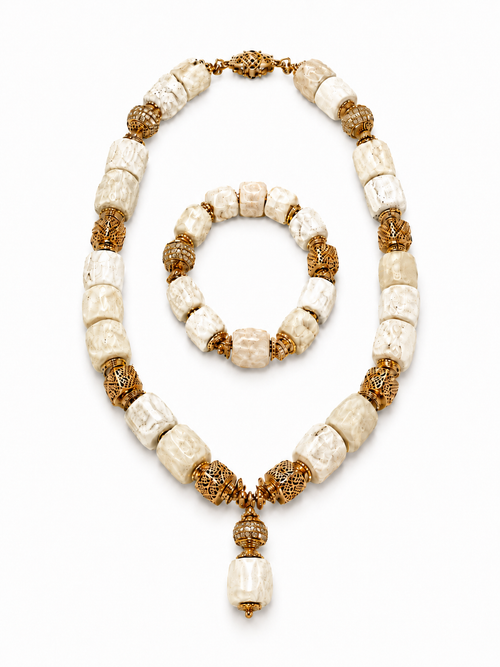 White coral necklace and matching coral bracelet set with gold beads on a white background